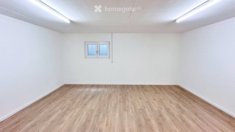 Empty room with white walls, wooden flooring, and a single window with frosted glass panels.