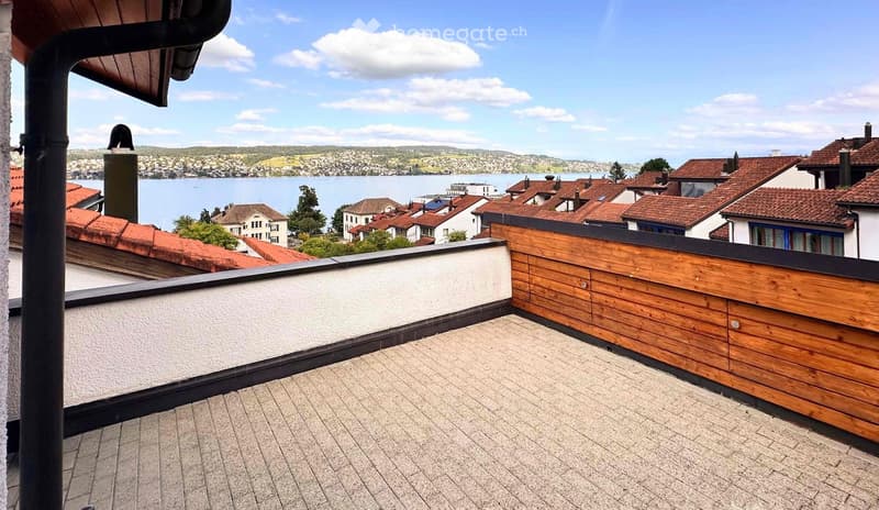 Roof terrace with wooden decking, white wall, wooden paneling, scenic view of lake and town.