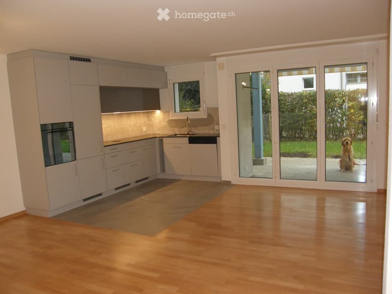 Modern kitchen with light-colored cabinets, a sink, and an oven, featuring large sliding glass doors leading to an outdoor area.