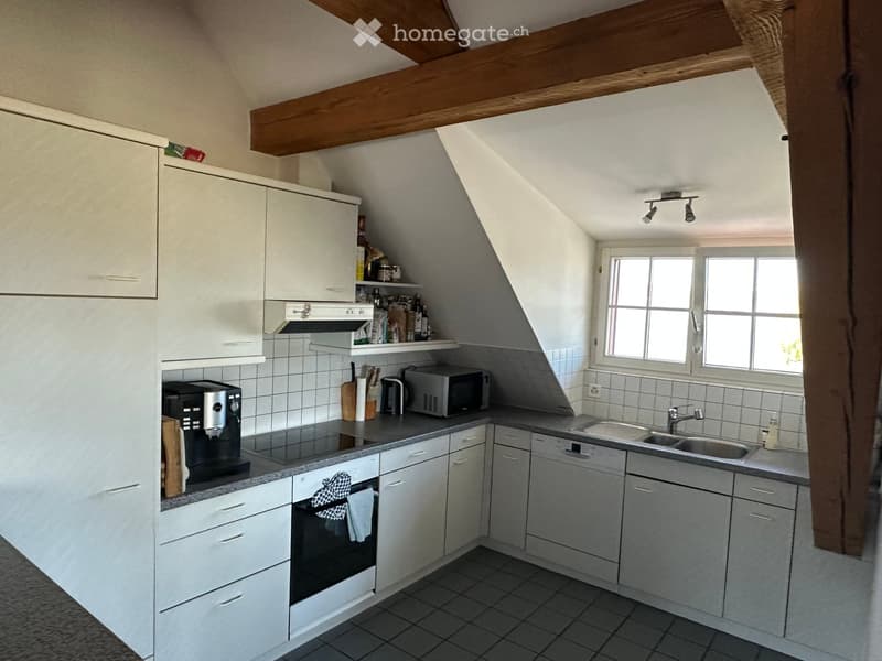 Modern kitchen with white cabinets, stainless steel appliances, and a grey countertop. Features include a coffee maker, microwave, oven, sink, and faucet.