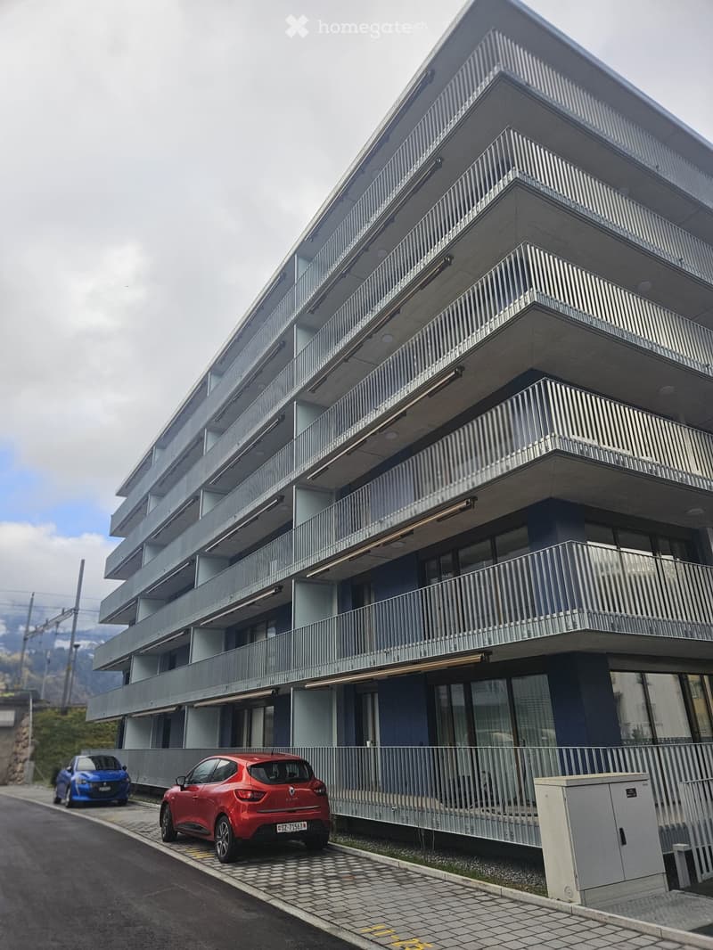 residential building with multiple floors, balconies, parking spaces in front