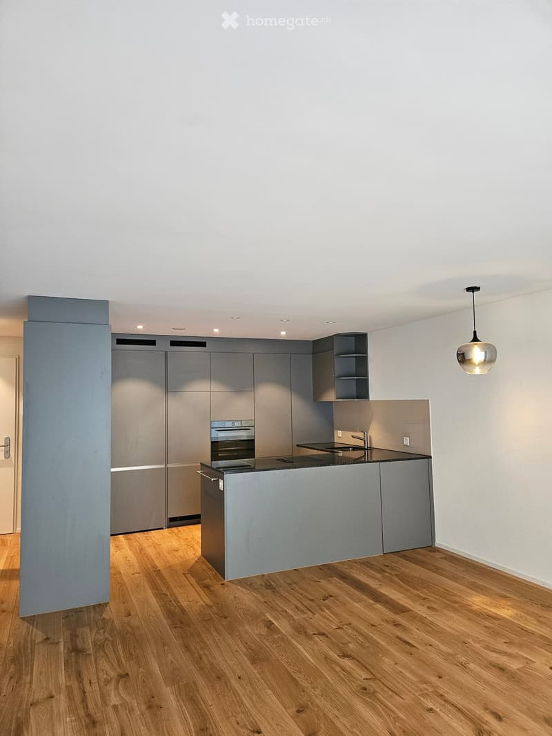 Kitchen. Modern kitchen with grey cabinets, wooden flooring, and a central island with an oven and sink.