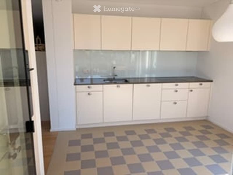 Modern kitchen with white cabinets, a sink, and a checkered tile floor.