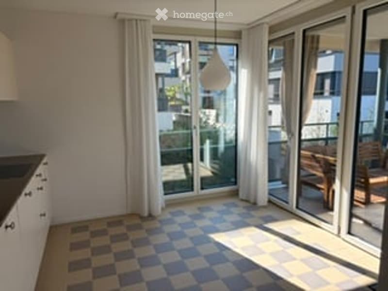 Bright, unfurnished room with large windows and a checkered floor. The space is empty, showing only the walls, floor, and windows.
