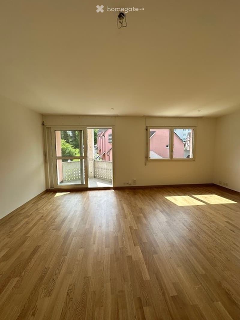 Empty room with hardwood floors, white walls, sliding glass doors, and windows. No furniture or equipment.