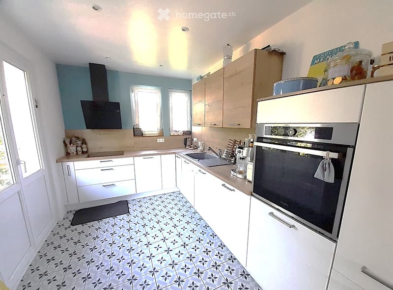 Modern kitchen with white cabinets, stainless steel appliances, and a blue and white patterned tile floor.