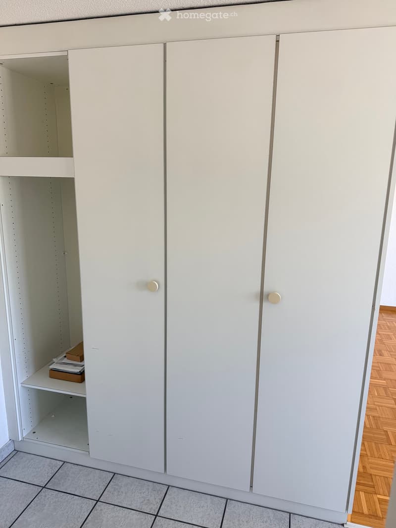 White cabinet with shelves and a small box on the shelf.