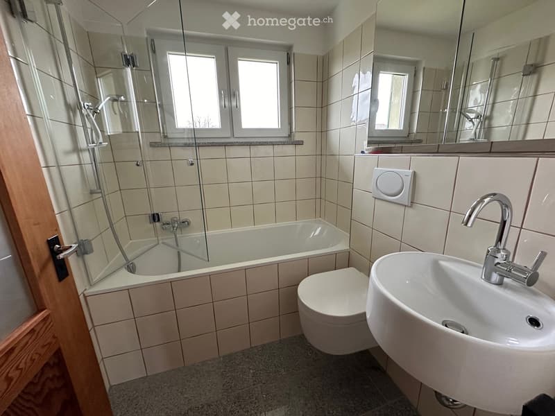 white tiled walls, bathtub with shower, white sink, white toilet, mirror, window