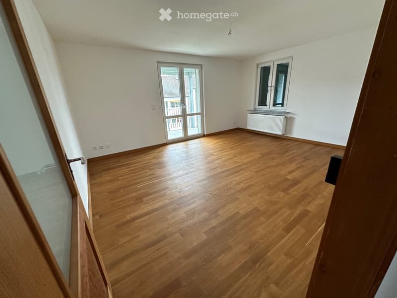 empty room, wooden floor, white walls, large glass sliding doors leading to balcony, power outlets, window with radiator