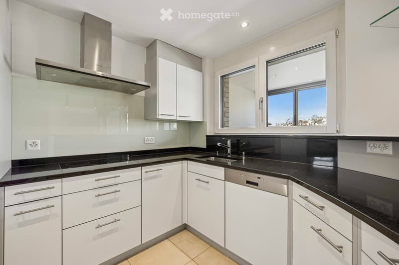 Kitchen. Modern kitchen with white cabinets, black countertops, stainless steel range hood, and a sink with a faucet.