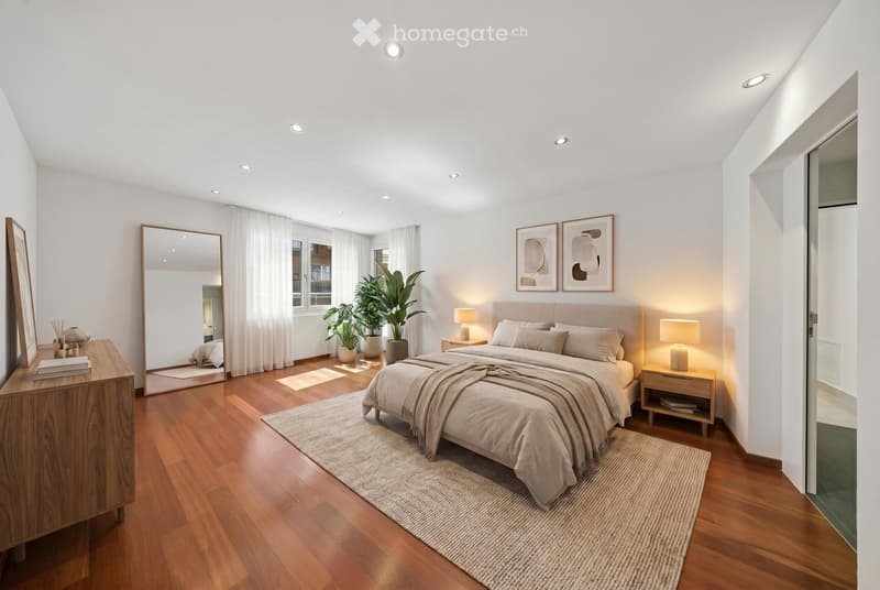 Bedroom. Spacious bedroom with wooden floors, large bed, nightstands, lamps, and a mirror. Potted plants and artwork on the wall.