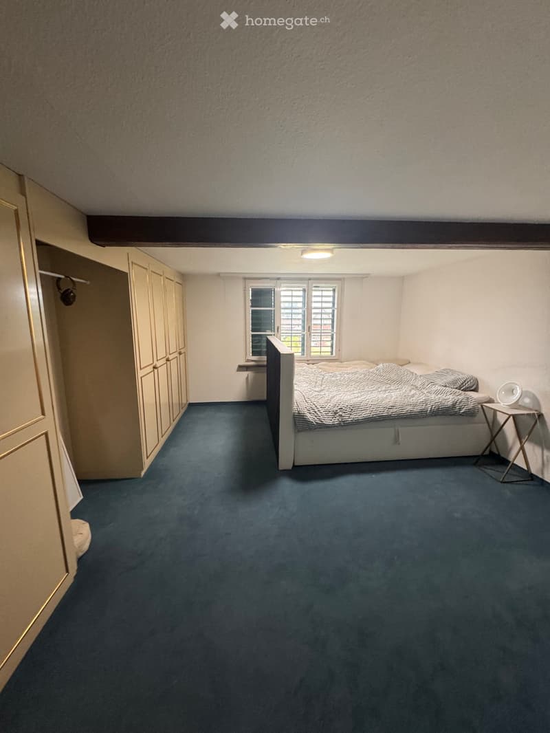 Bedroom with a blue carpet, a bed with bedding, a nightstand, and a wardrobe.