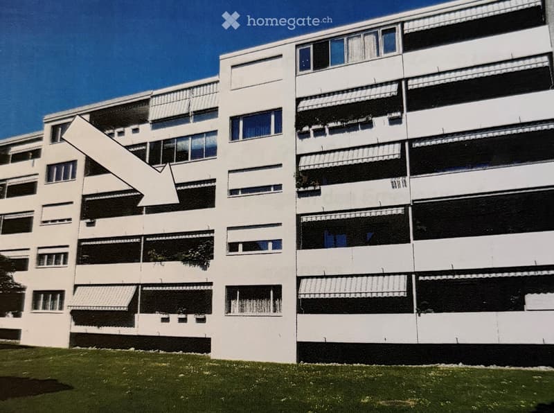Modern multi-story residential building with white facade, large windows, and balconies with awnings.