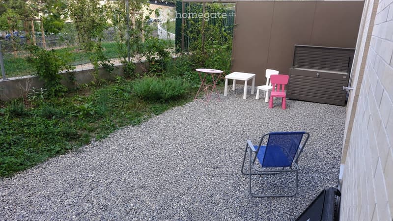 Small outdoor area with gravel ground, small tables, chairs, and a storage unit against the wall.