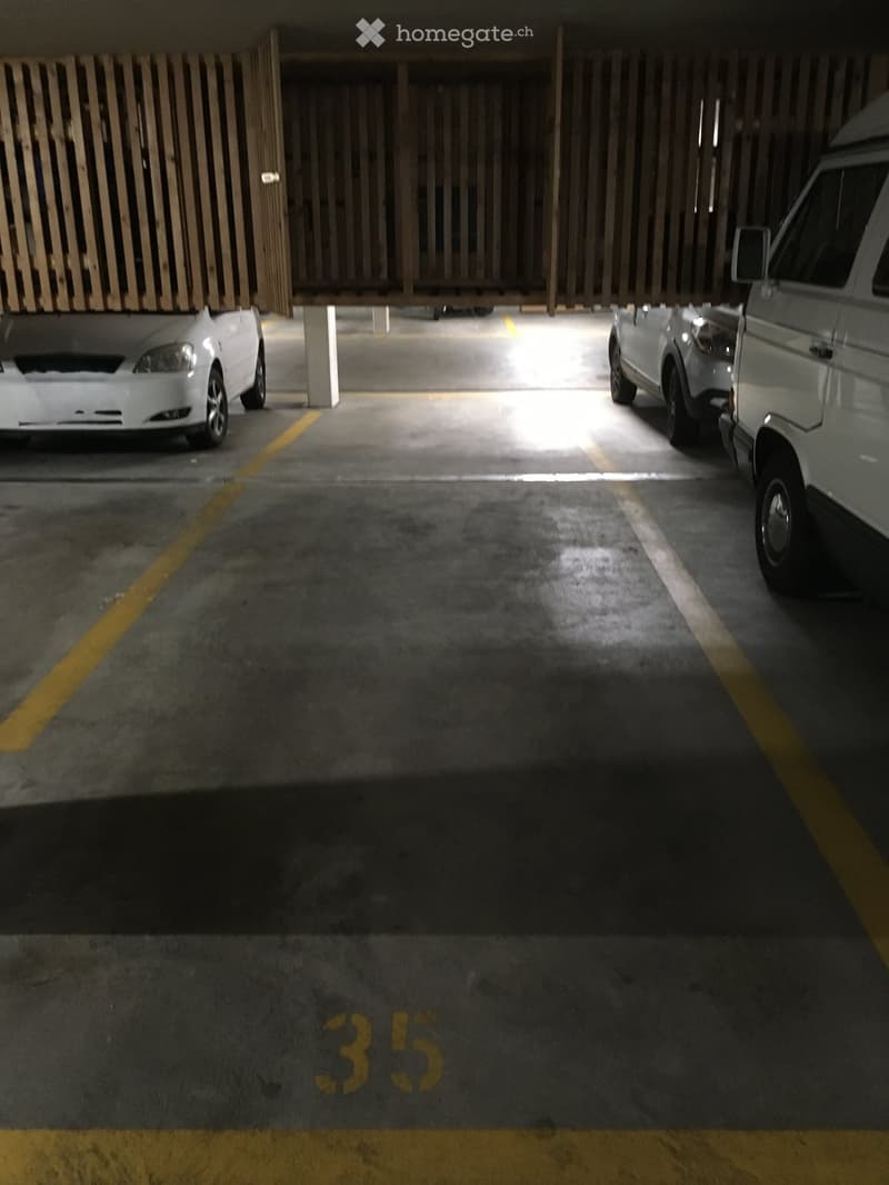 Parking area with cars, yellow lines, concrete floor, number 35 on the floor