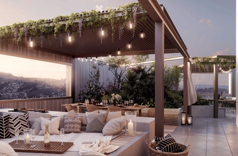 A modern rooftop terrace with a view, featuring a seating area with pillows, a dining table with chairs, and string lights.