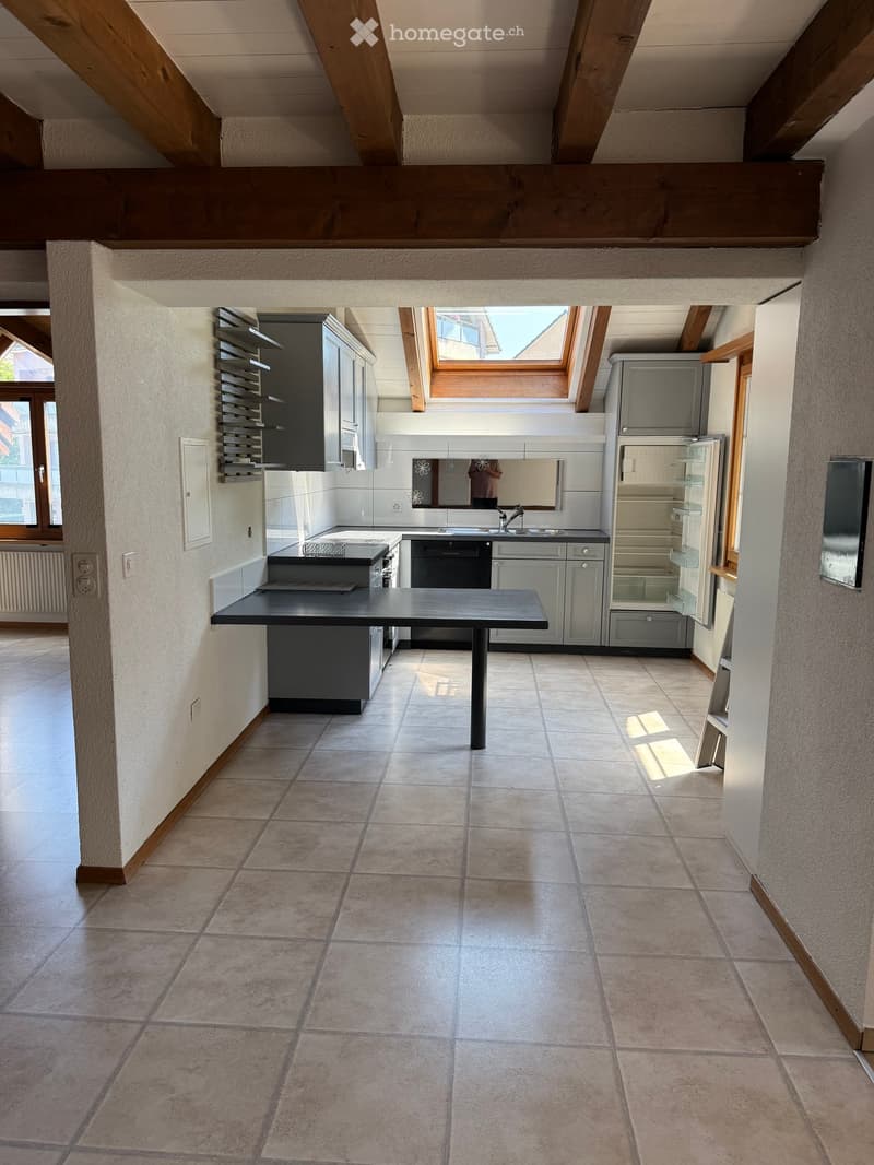 Modern kitchen with tiled floor, grey cabinets, stainless steel appliances, and a central island table.
