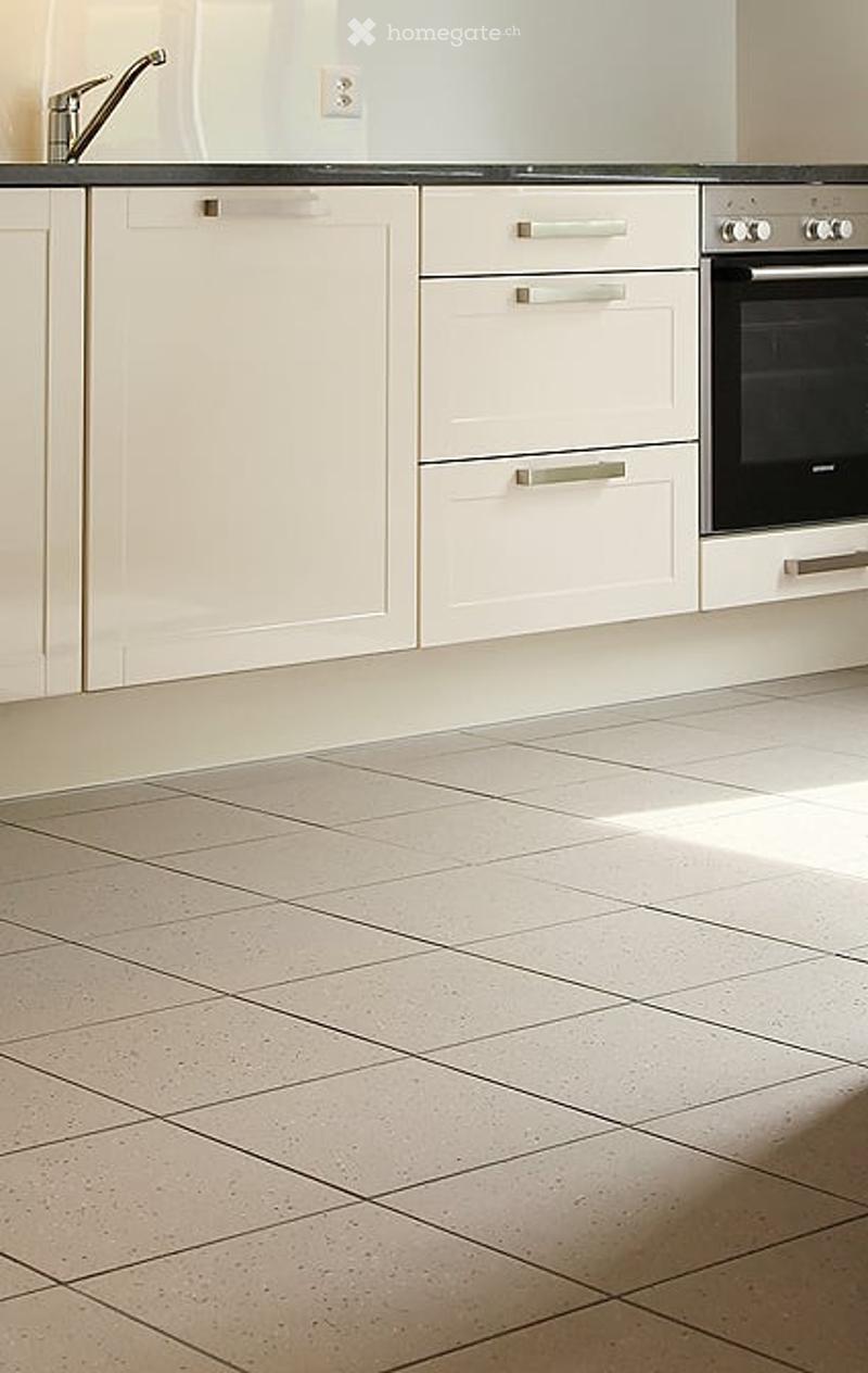 Modern kitchen with white cabinets, a stainless steel faucet, and a built-in oven. The floor is tiled in a light beige color.