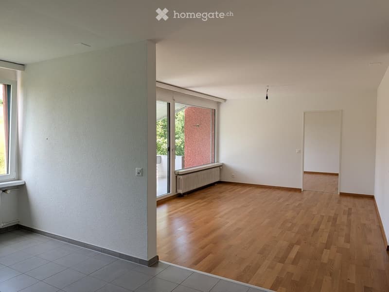 Empty room with wooden flooring, white walls, and large windows. No furniture or equipment present.