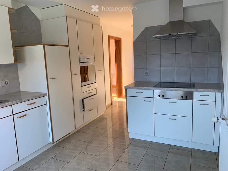 Modern kitchen with white cabinets, stainless steel appliances, granite countertops, and tiled flooring.