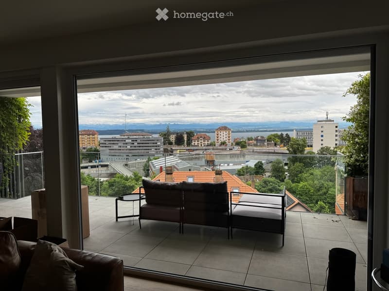 Balcony with a panoramic city view, featuring a sofa, chairs, and a small table.