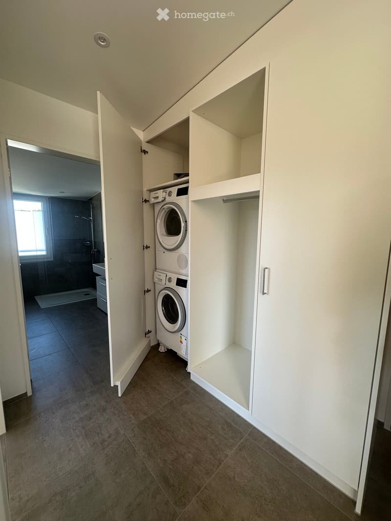 Laundry room with a washing machine, white cabinet, and tiled floor.