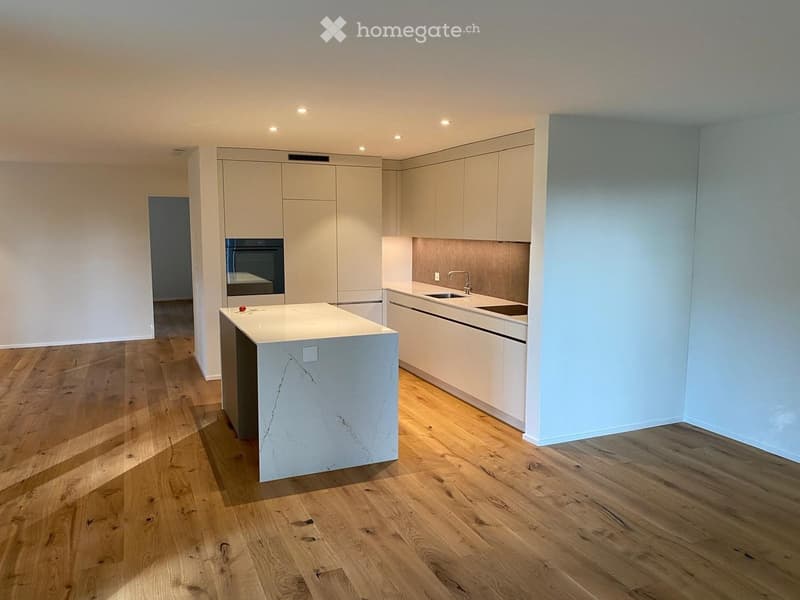 Modern kitchen with white cabinets, a central island, and wooden flooring.