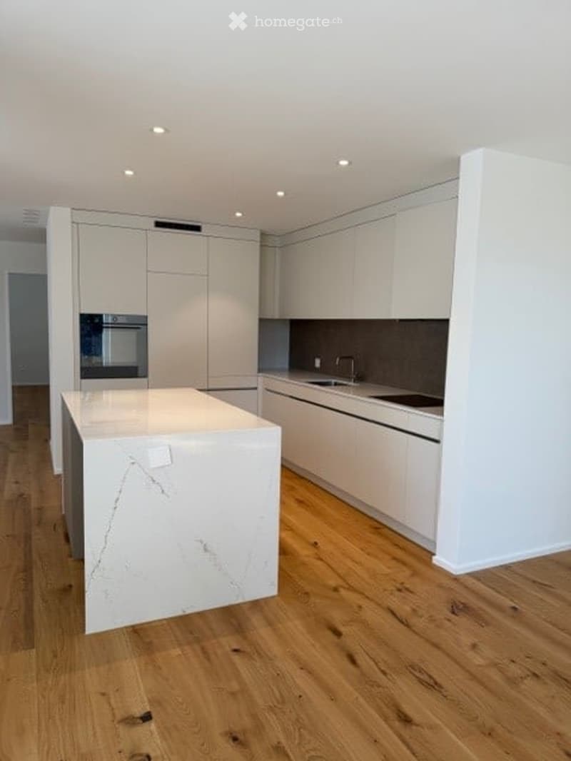 Modern kitchen with white cabinets, a central island with marble countertop, and a sink with a faucet.