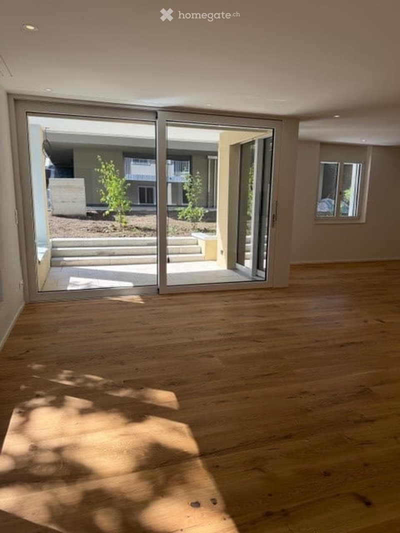 Empty room with wooden flooring and large sliding glass doors leading to an outdoor area. No furniture or equipment present.