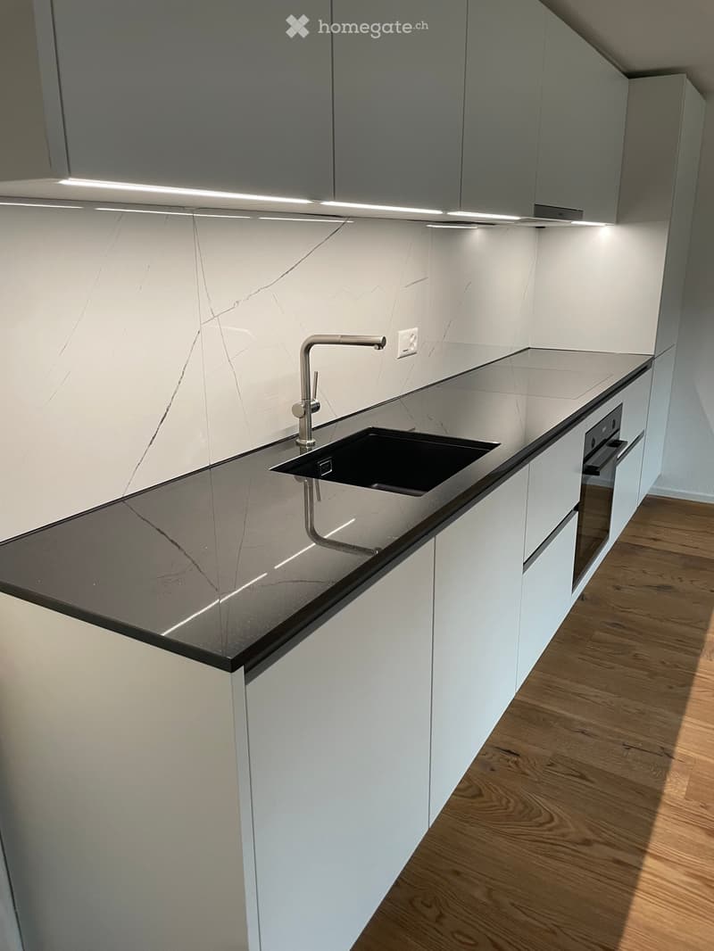 Modern kitchen with white cabinets, marble countertops, and a sleek stainless steel sink and faucet.