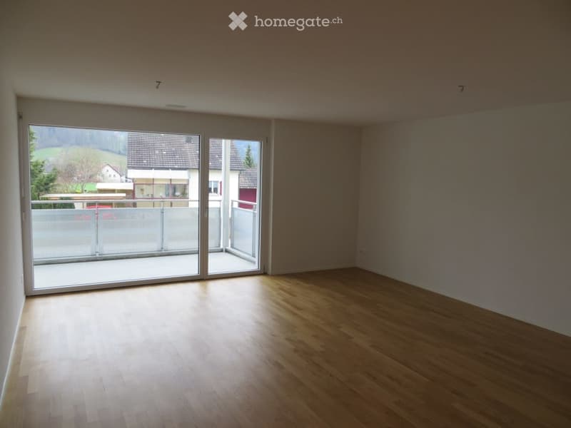 Empty room with wooden flooring and large sliding glass doors leading to a balcony.