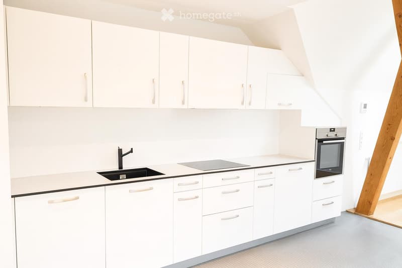 Modern white kitchen with sleek cabinets, a sink, stove, and oven, featuring a clean and minimalist design.
