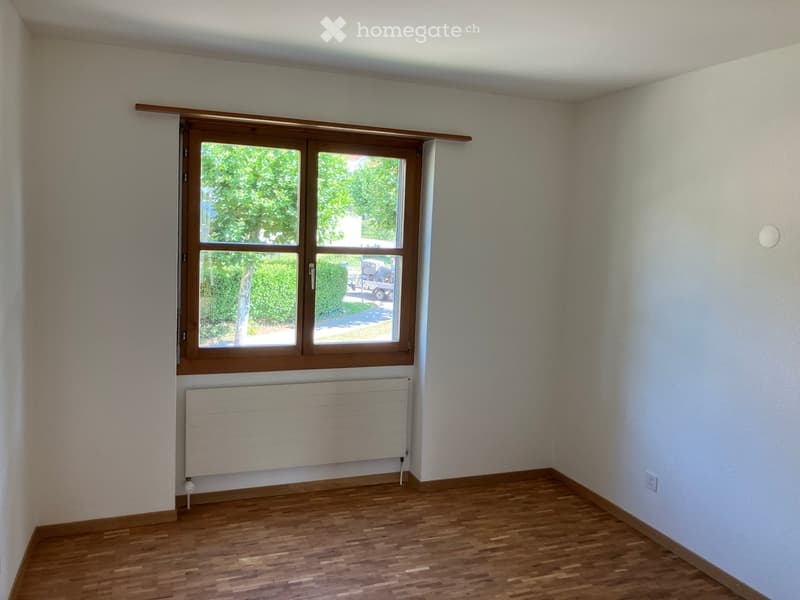 Unfurnished Room. Empty room with wooden flooring, white walls, a window with wooden frame, and a radiator below the window.