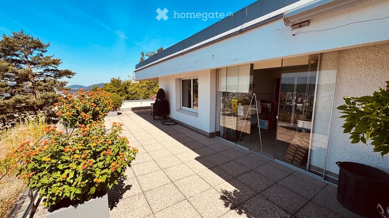 Balcony area with tiled flooring, glass sliding doors leading to the interior, potted plants, and a scenic view of trees and mountains.