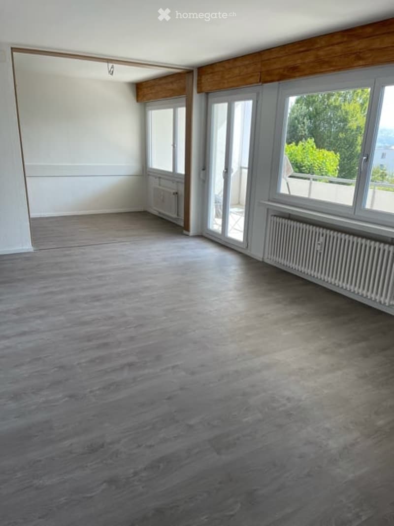 Empty room with wooden flooring, white walls, large windows, and radiators. No furniture or equipment present.