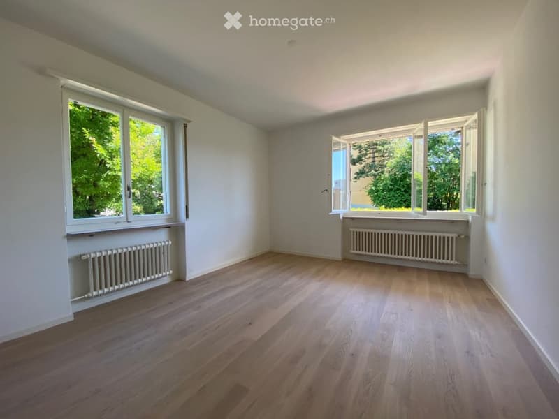 empty room, wooden floor, white walls, two large windows, white radiators