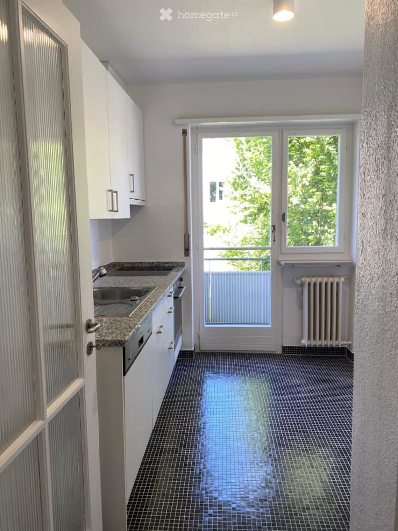 modern kitchen with white cabinets, granite countertop, stainless steel sink, dishwasher, and a balcony with a view