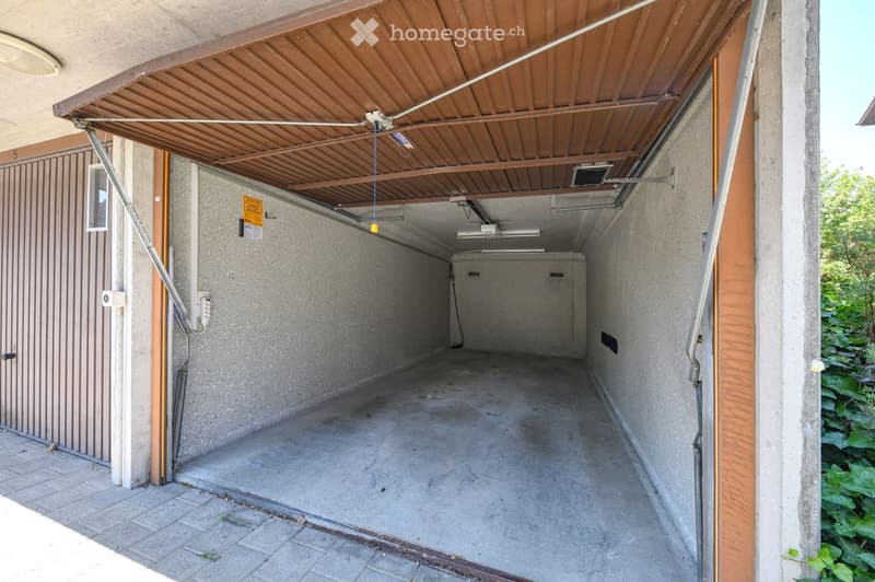 {"type": "Garage", "objects": [], "description": "Empty garage with concrete walls and floor, covered by a retractable roof, with a small entrance area and some electrical fixtures visible.", "localized_descriptions": {"EN": "Empty garage with concrete wa