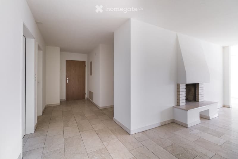 Empty hallway with white walls, tiled floor, and a fireplace on the right side.