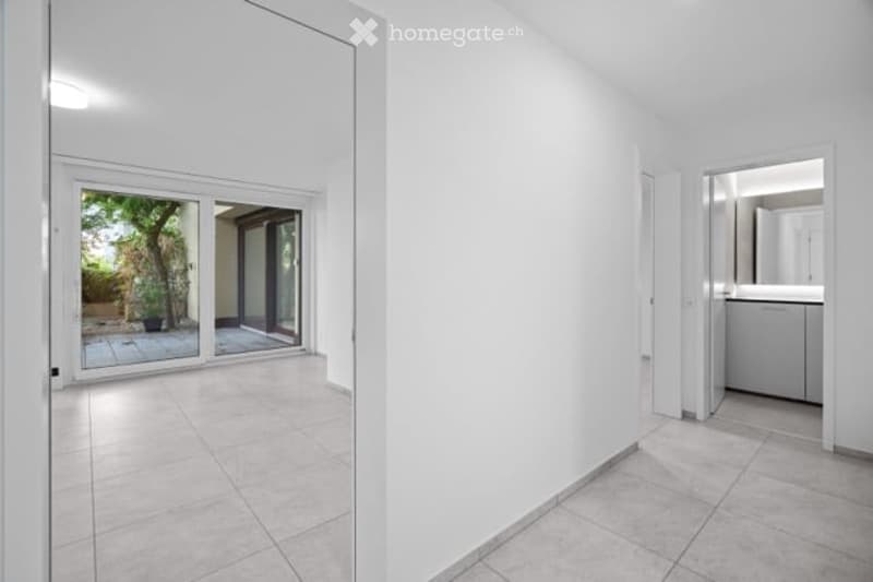 Empty unfurnished room with white walls, tiled floor, and large sliding glass doors leading to a balcony or outdoor area.