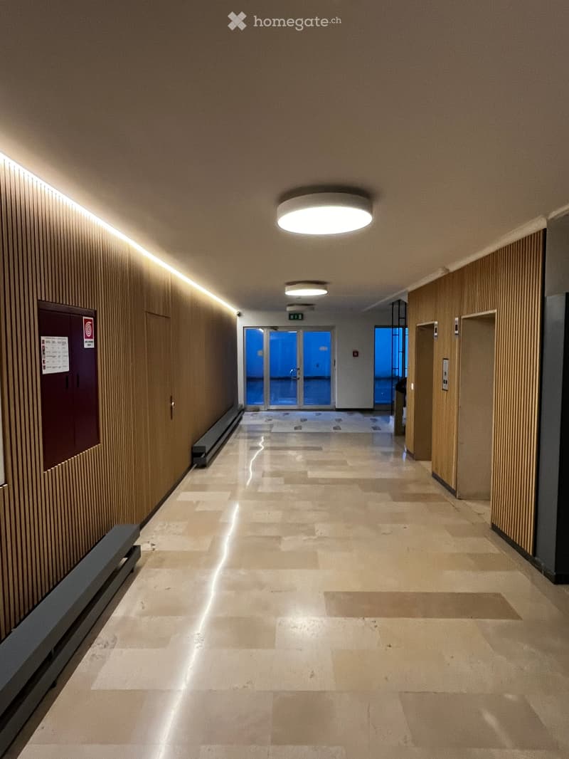 Empty hallway with wooden walls, tiled floor, and ceiling lights