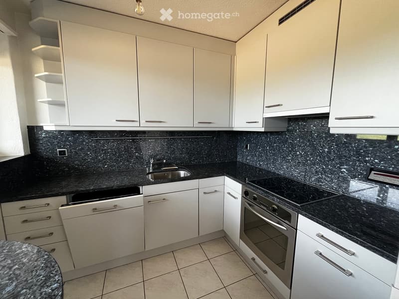 Modern kitchen with white cabinets, black granite countertops, and stainless steel appliances including a sink, oven, and dishwasher.