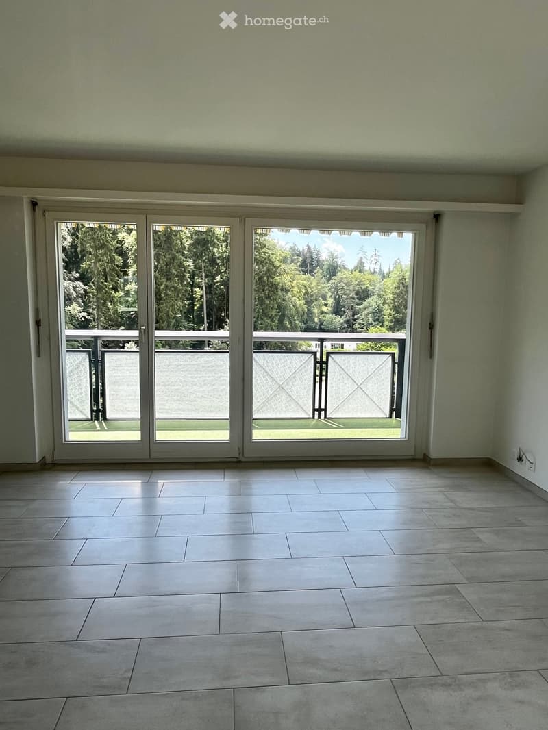 Empty room with large sliding glass doors leading to a balcony, tiled floor, and light-colored walls.