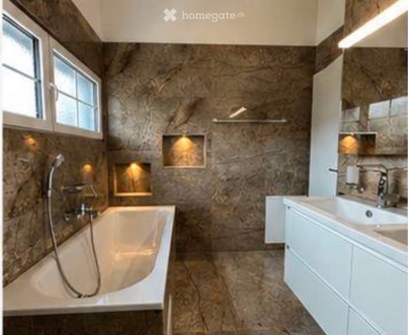 Elegant bathroom with marble walls and floors, featuring a bathtub, double sink, and modern fixtures.