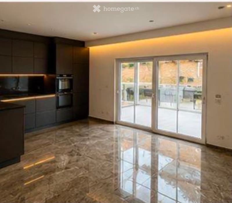 Modern kitchen with dark cabinets, a built-in oven, and a large sliding glass door leading to a balcony or terrace.