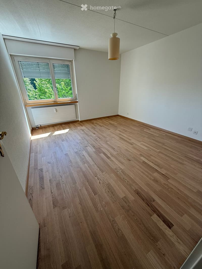 empty room, wooden floor, white walls, window with blinds, radiator, power outlets