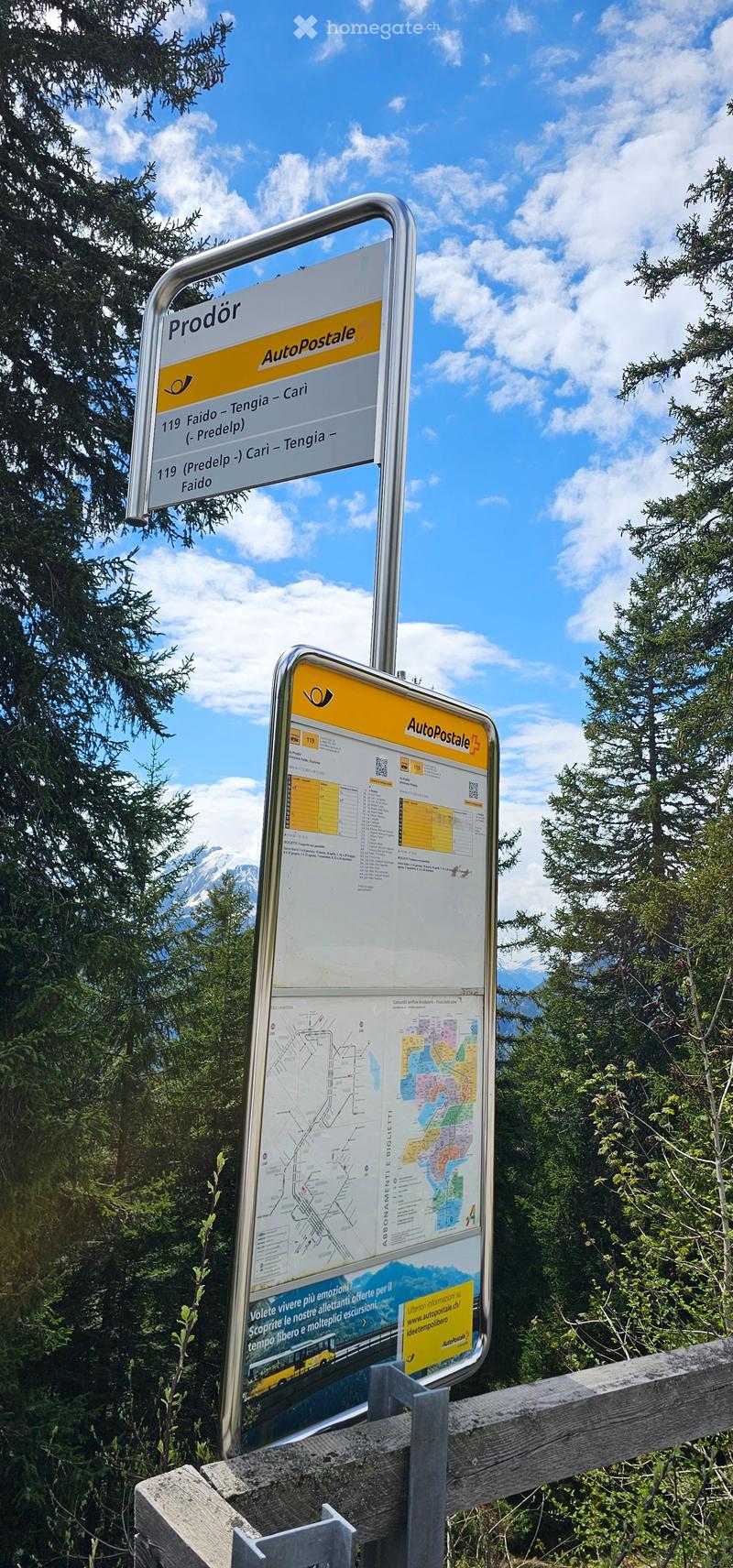 Two directional signs mounted on a wooden fence, displaying route numbers and destinations, with a map and additional information on one sign.