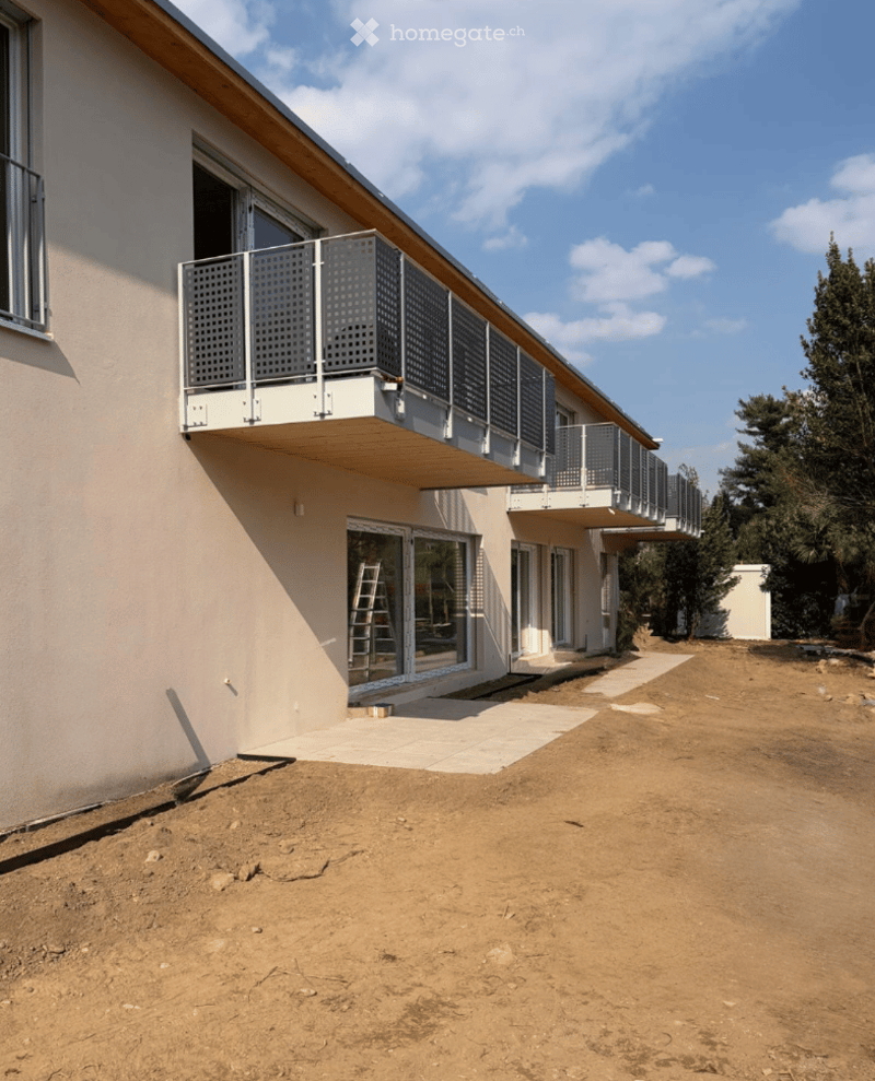 Modern two-story building with a balcony, large windows, and a partially constructed exterior.