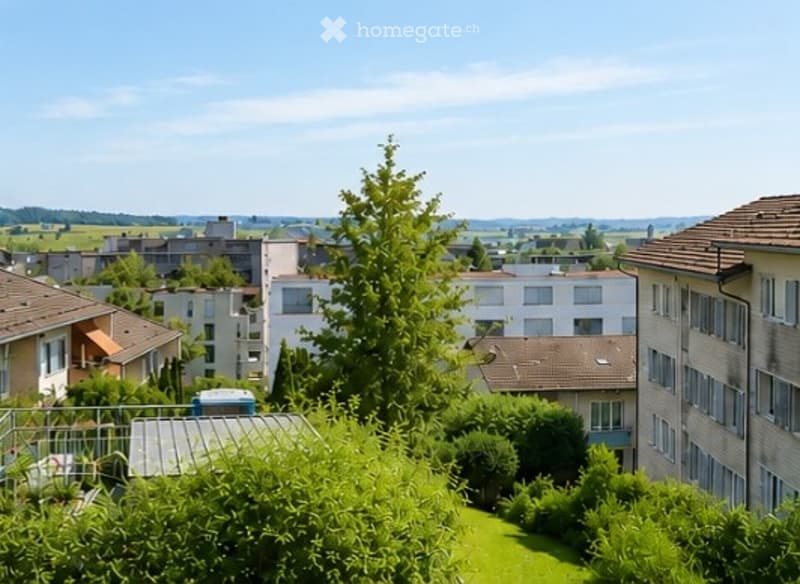 View from a balcony or terrace showing a residential area with multiple apartment buildings, trees, and a clear blue sky.