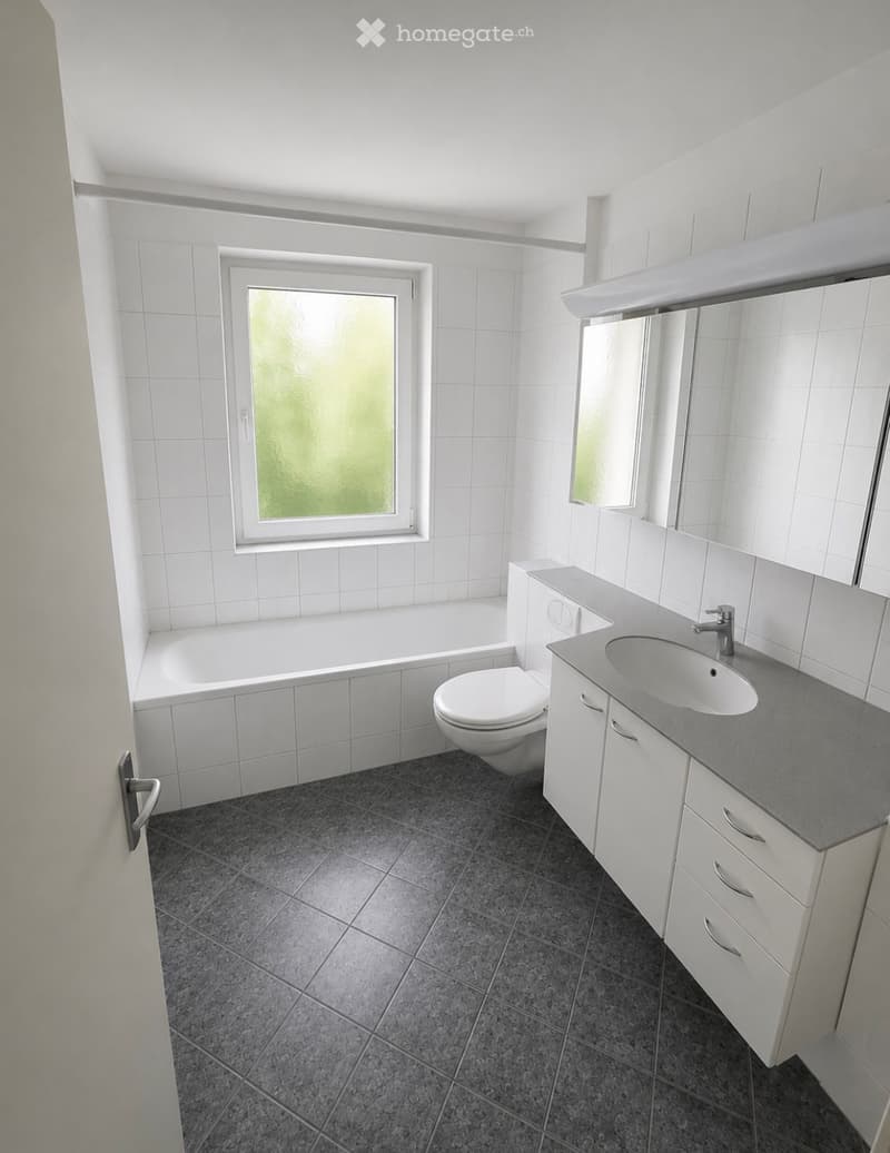 Modern bathroom with white tiles, a bathtub, toilet, sink, and a mirrored cabinet.